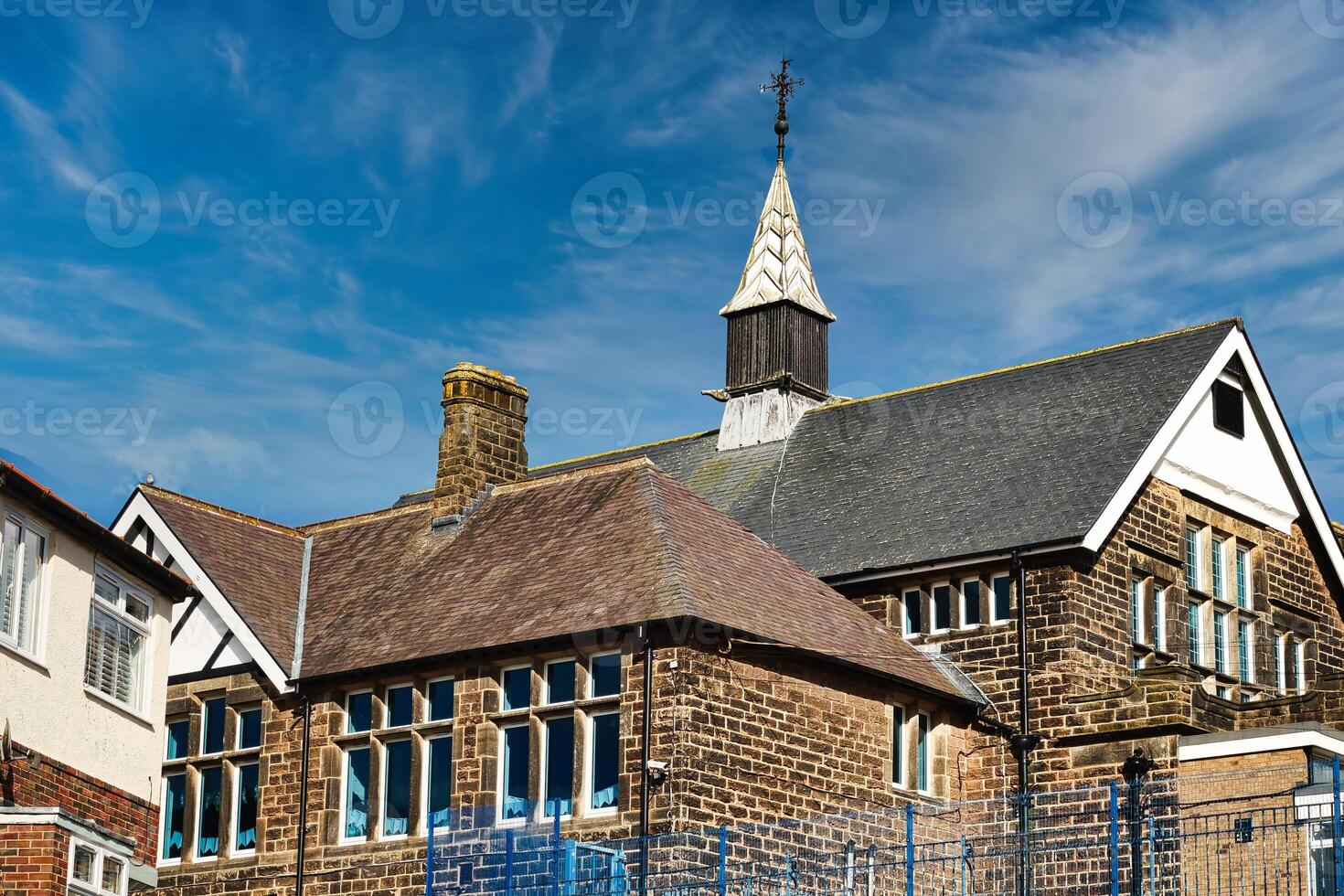 traditionnel brique école bâtiment avec une flèche contre une bleu ciel avec vaporeux des nuages dans harroquer, Nord Yorkshire. photo