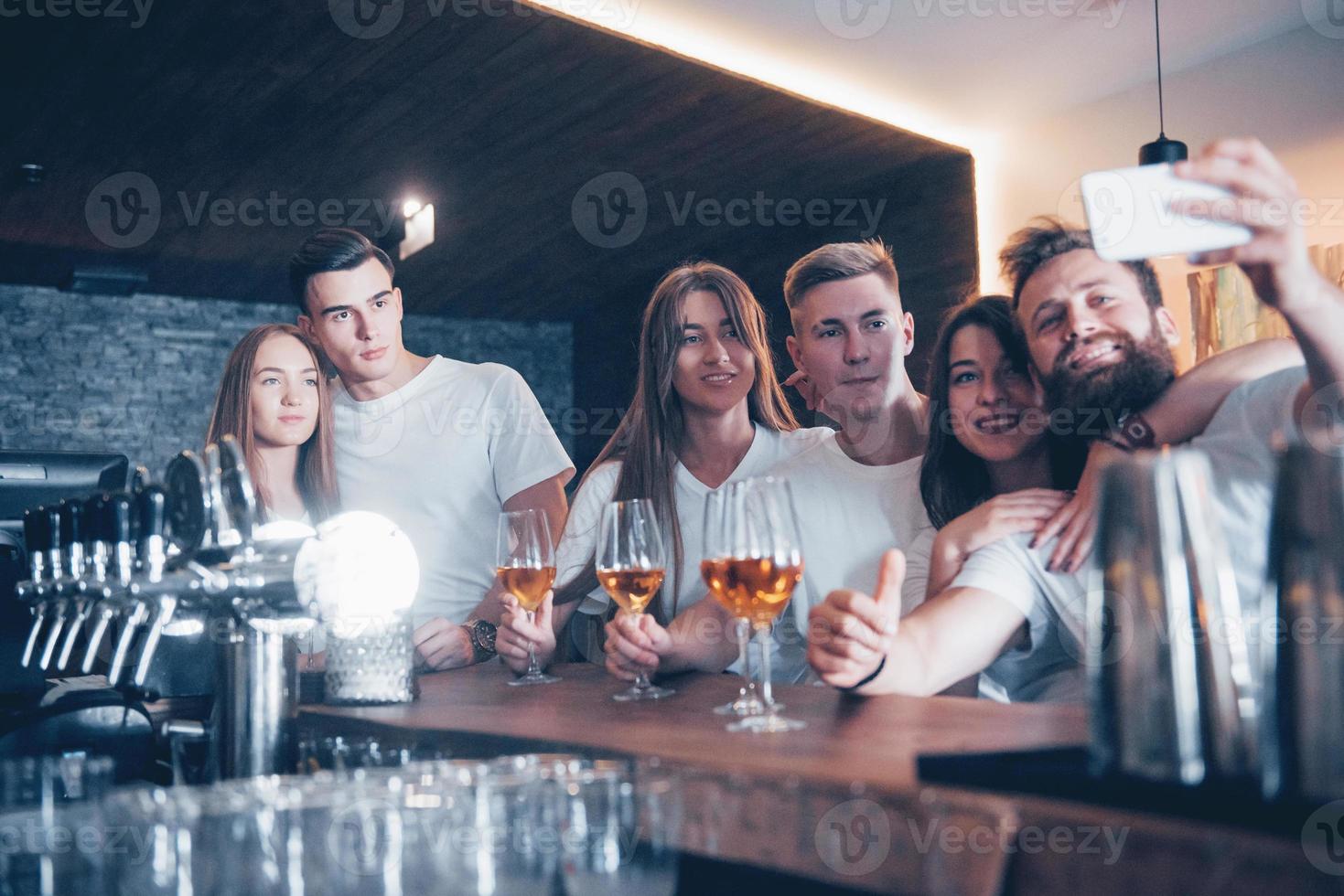 concept de loisirs et de communication. groupe d'amis souriants heureux appréciant des boissons et parlant au bar ou au pub photo