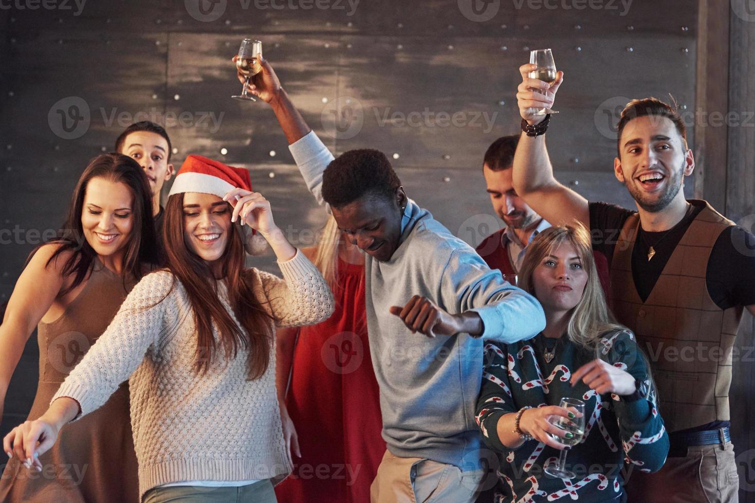 faire la fête avec des amis. ils aiment Noël. groupe de jeunes joyeux portant des cierges magiques et des flûtes à champagne dansant à la fête du nouvel an et ayant l'air heureux. concepts sur le mode de vie ensemble photo