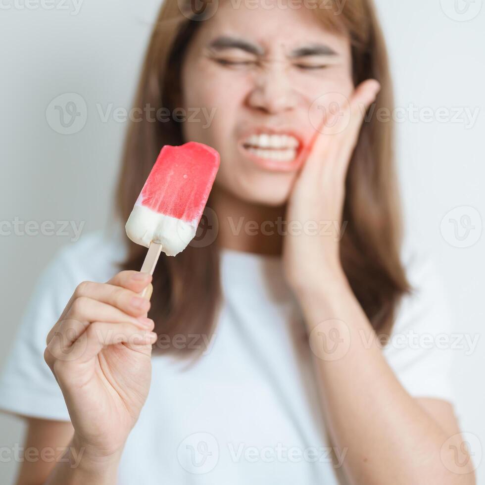 les dents sensible à du froid concept. femme tenir la glace crème et ayant mal aux dents et douleur après manger. dent pourriture ou gencive maladie, broyage les dents et stress, exposé nerf racines, fissure et fuyant les gencives photo