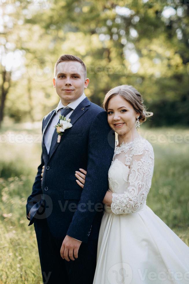 le marié et la mariée marchent dans la forêt près d'une rivière étroite photo