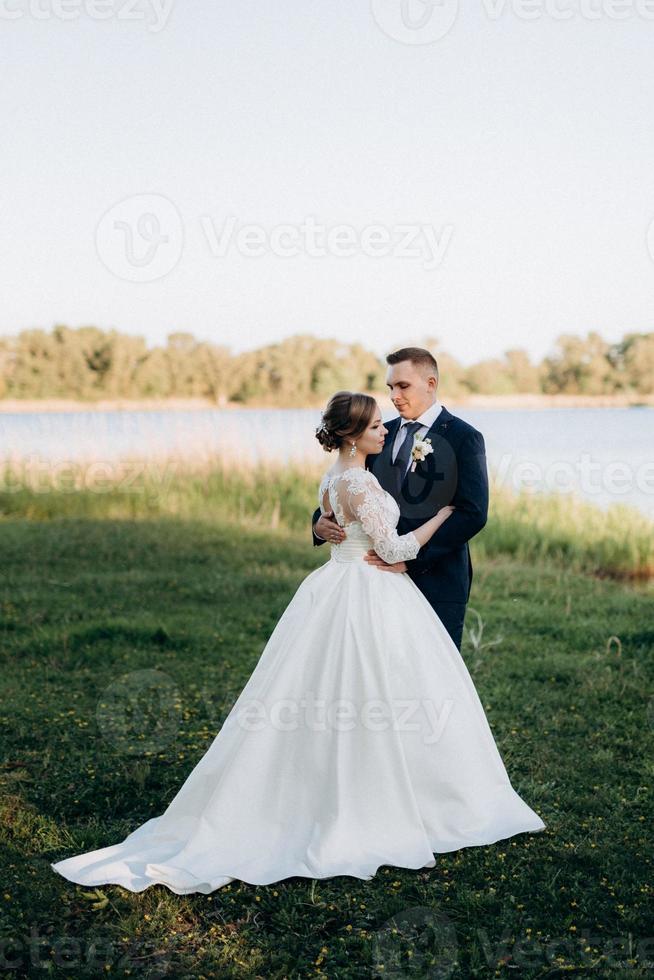 le marié et la mariée marchent dans la forêt près d'une rivière étroite photo