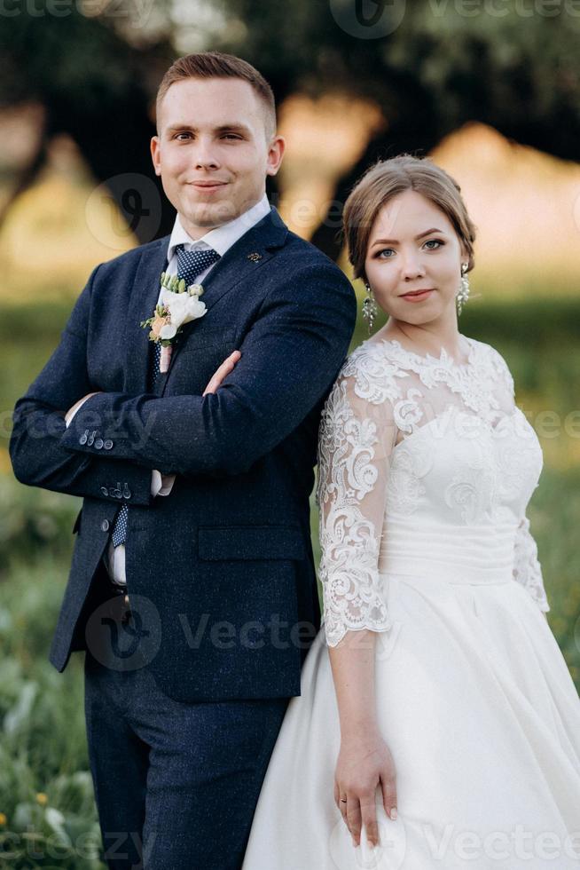 le marié et la mariée marchent dans la forêt près d'une rivière étroite photo