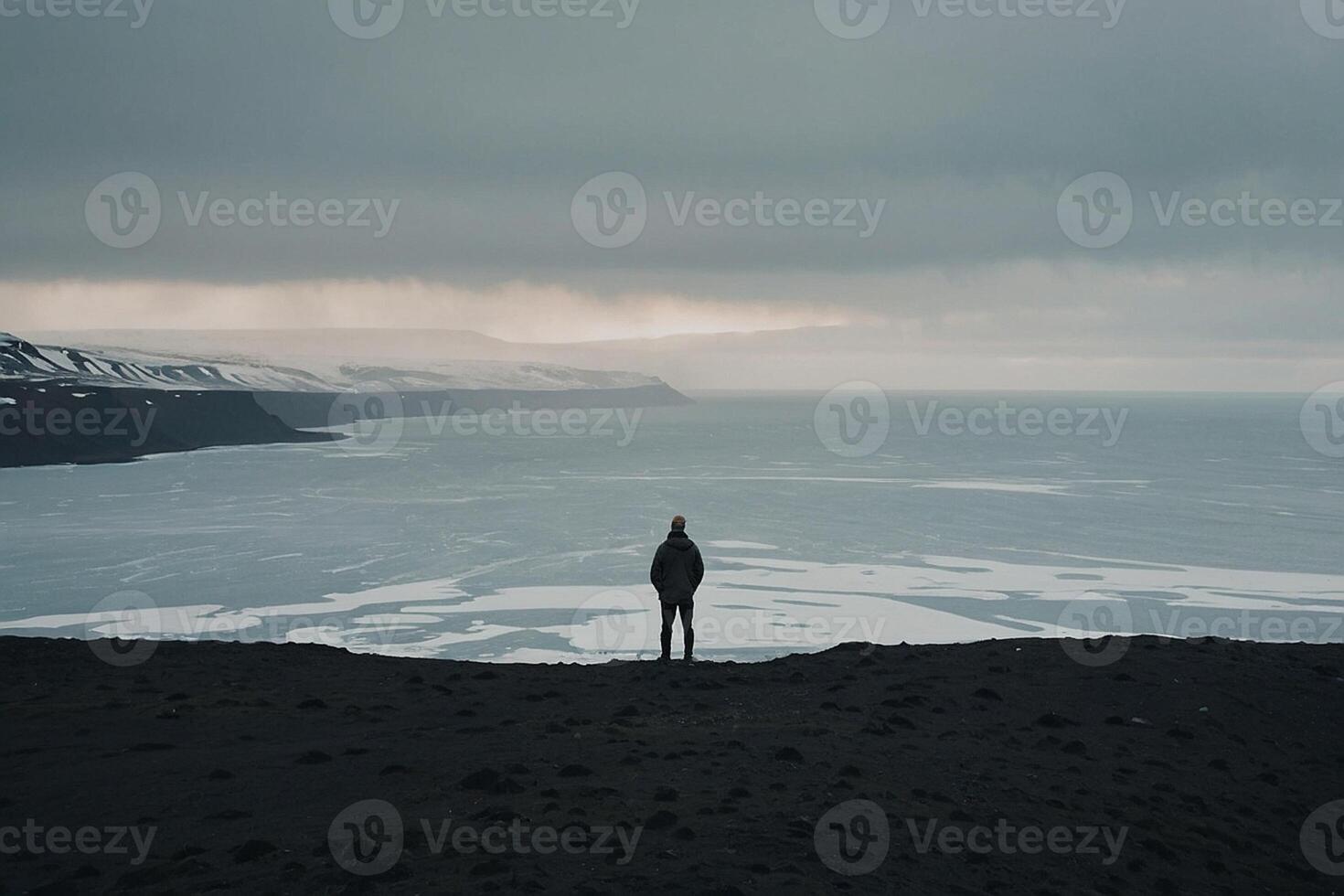 une homme permanent sur le bord de une falaise surplombant le océan photo