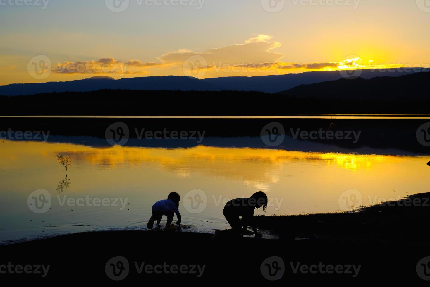 silhouettes d'enfants heureux jouant sur le lac à l'heure du coucher du soleil, réservoir amphoe wang saphung loei thaïlande photo