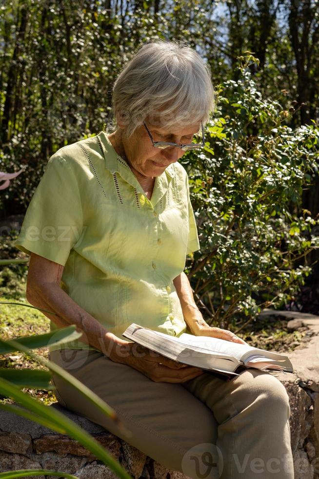 femme mûre élégante lisant un livre dans le jardin photo