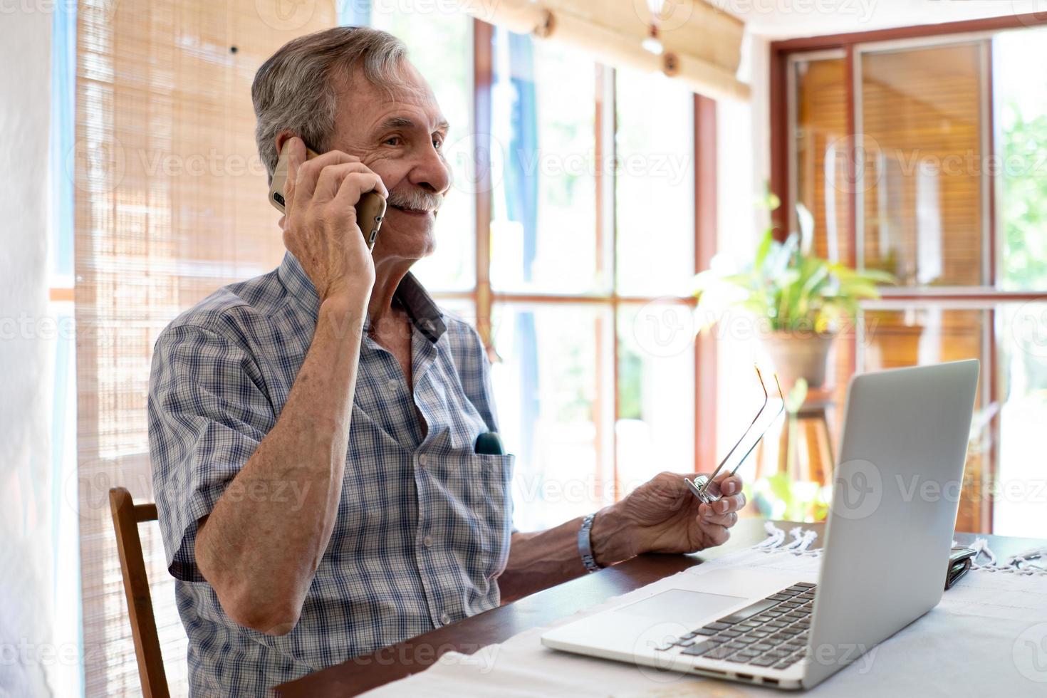 gros plan homme d'affaires souriant parlant avec un téléphone tout en regardant un ordinateur portable photo