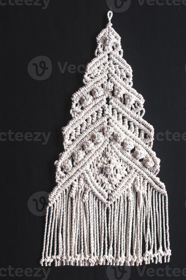 Macramé d'ornement d'arbre de Noël à partir de fils de coton naturel blanc sur fond noir photo