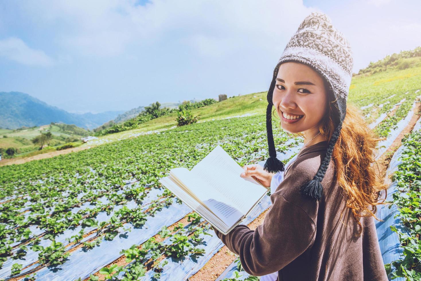 les femmes asiatiques se détendent pendant les vacances. étudier lire un livre. dans le parc aux fraises sur la montagne. en Thaïlande photo