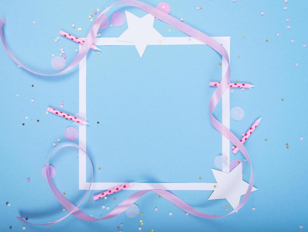 fond de vacances de fête avec ruban, étoiles, bougies d'anniversaire, cadre vide de boîte-cadeau et confettis sur fond bleu photo