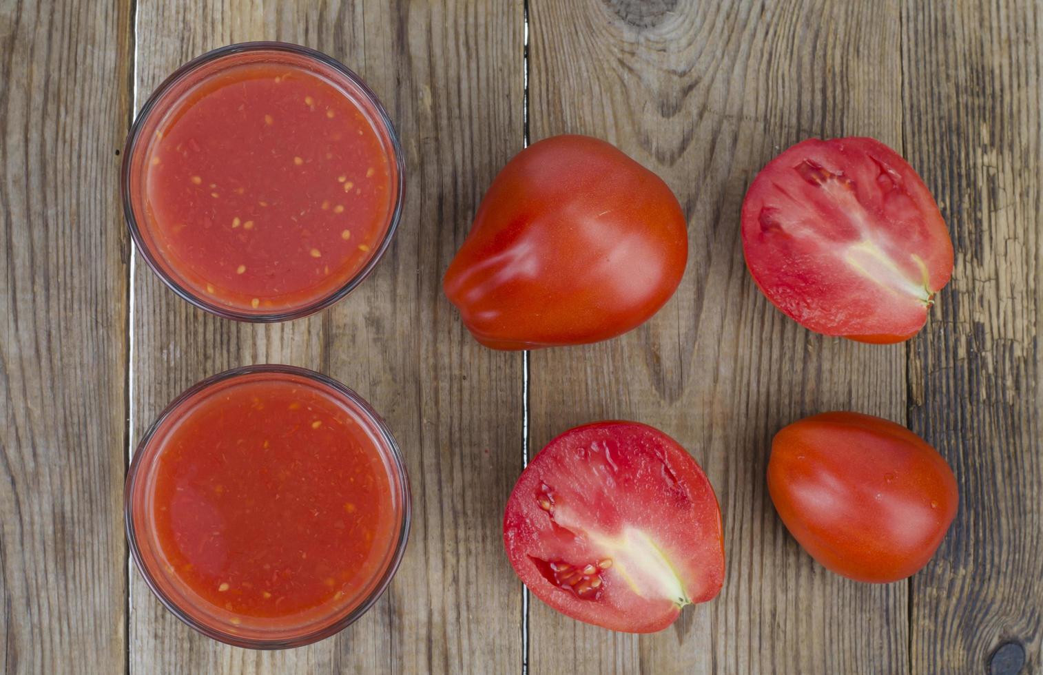 verres avec du jus de tomates rouges mûres sur table en bois photo