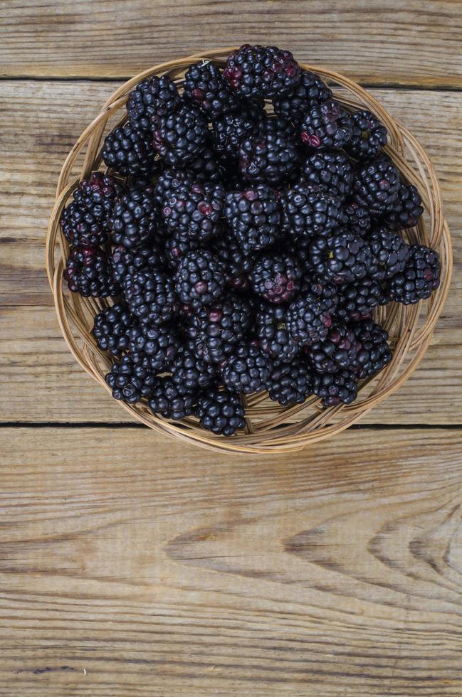 Mûres noires sucrées mûres dans un bol en bois photo