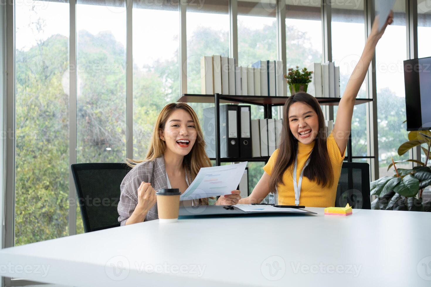 asiatique intelligent Bureau ou femme d'affaires excité réussi affaires personnes, célébrer gagner. deux femme d'affaires à la recherche à une mensuel sommaire de Ventes cette dépasser Ventes cibles et atteindre rentable croissance photo