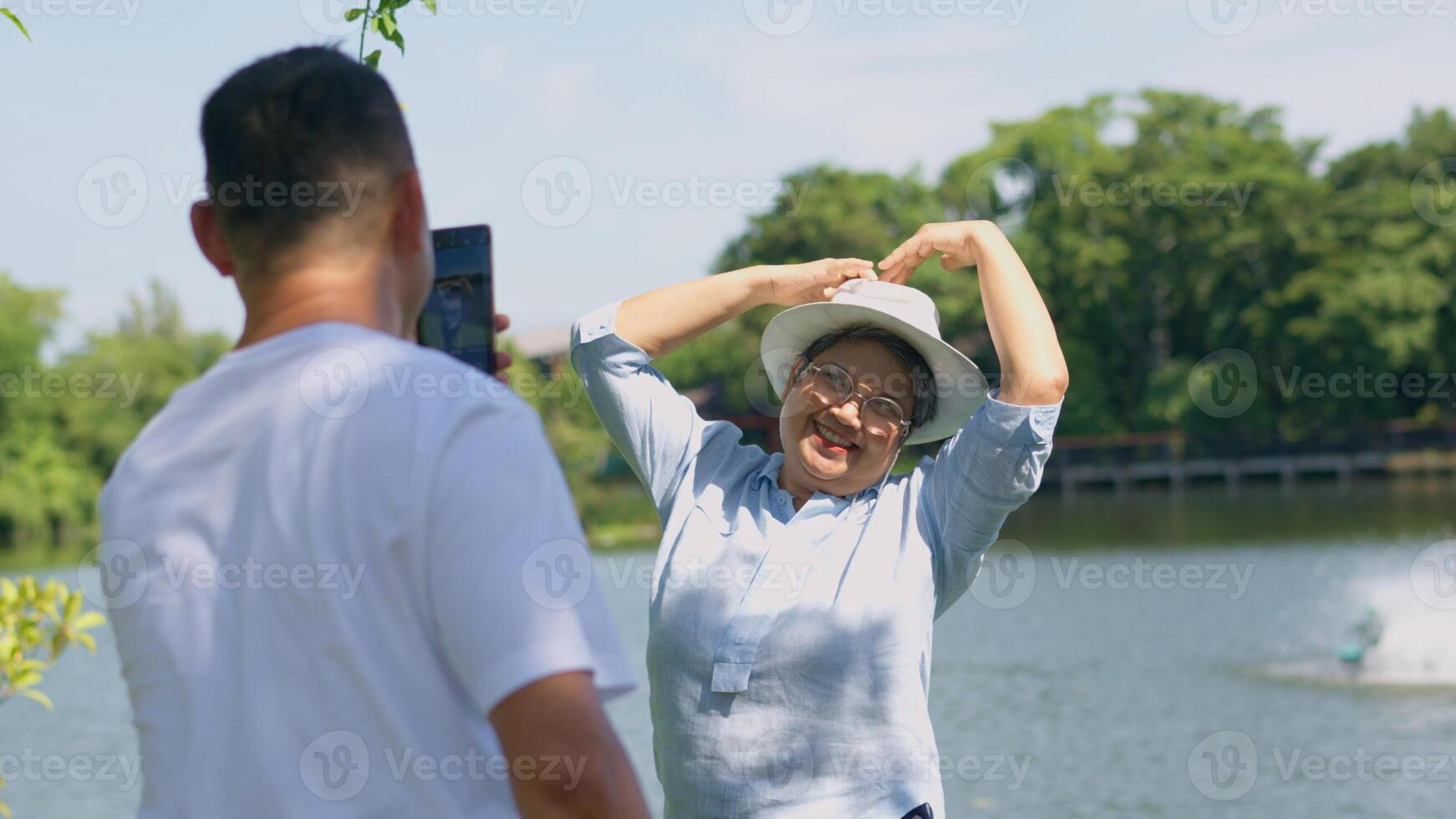 content et en bonne santé des couples asiatique photo et vlog selfie ensemble pour social médias dans parc sur loisirs. famille et relation amicale mode de vie, jouissance de actif personnes âgées, et Extérieur activité après retraite