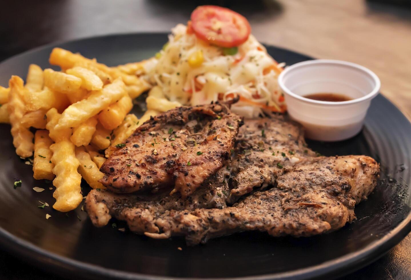 noir poivre mariné poulet filet avec Patate des bâtons sur une noir assiette photo