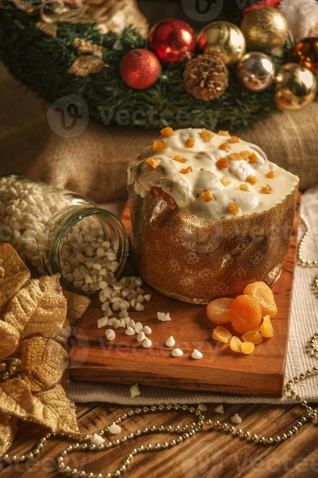 panettone au chocolat blanc à l'abricot séché sur table en bois avec des décorations de noël photo