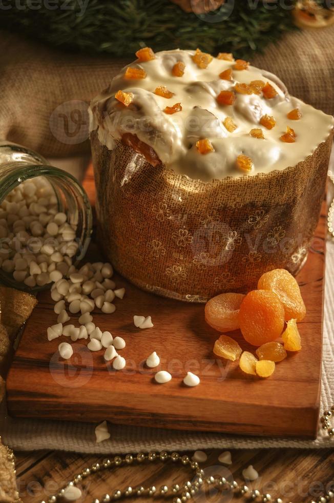 panettone au chocolat blanc à l'abricot séché sur table en bois avec des décorations de noël photo