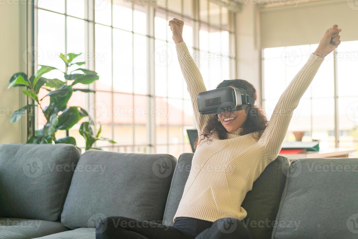 femme latine à l'aide d'un casque de réalité virtuelle sur canapé photo