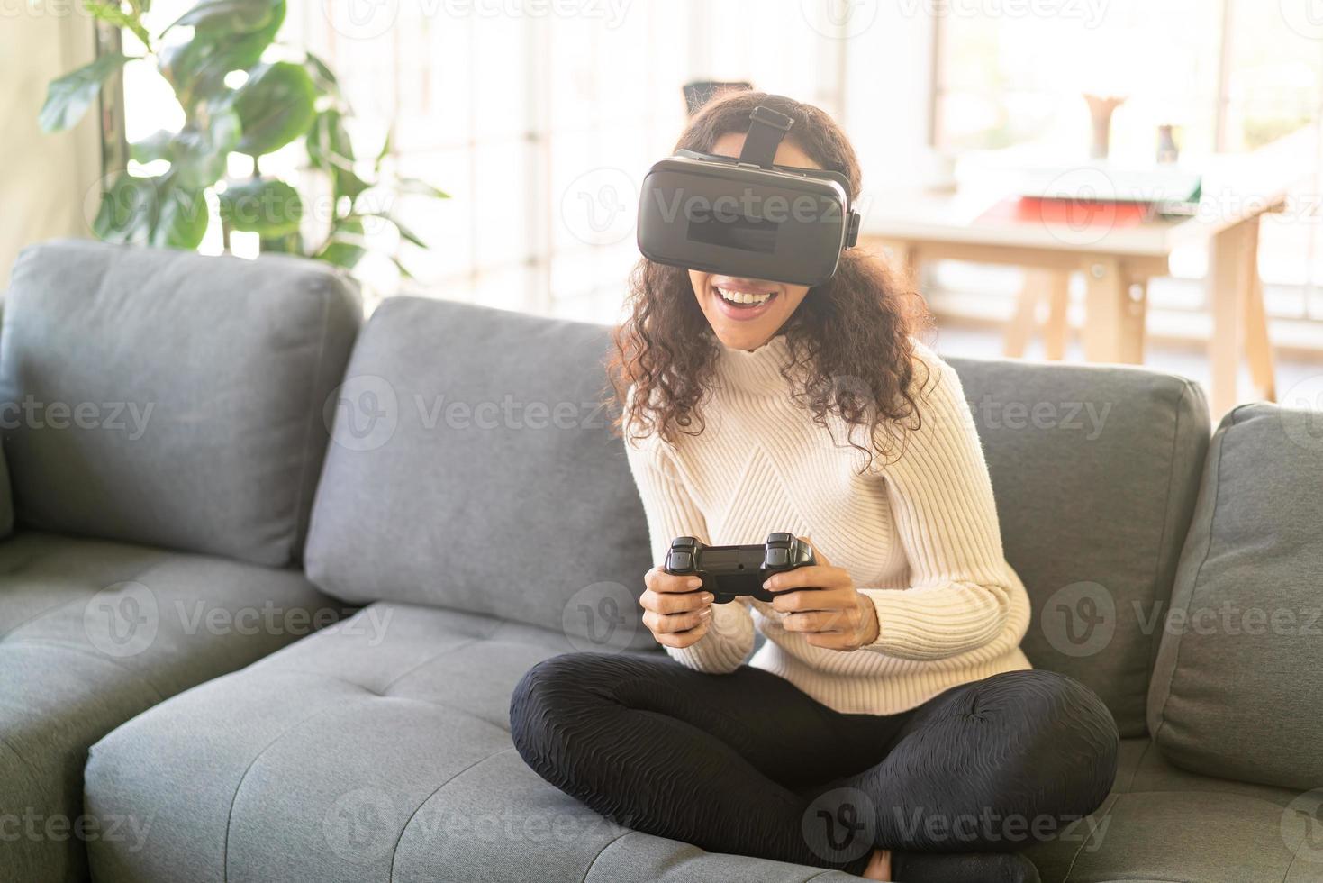 femme latine à l'aide d'un casque de réalité virtuelle sur canapé photo