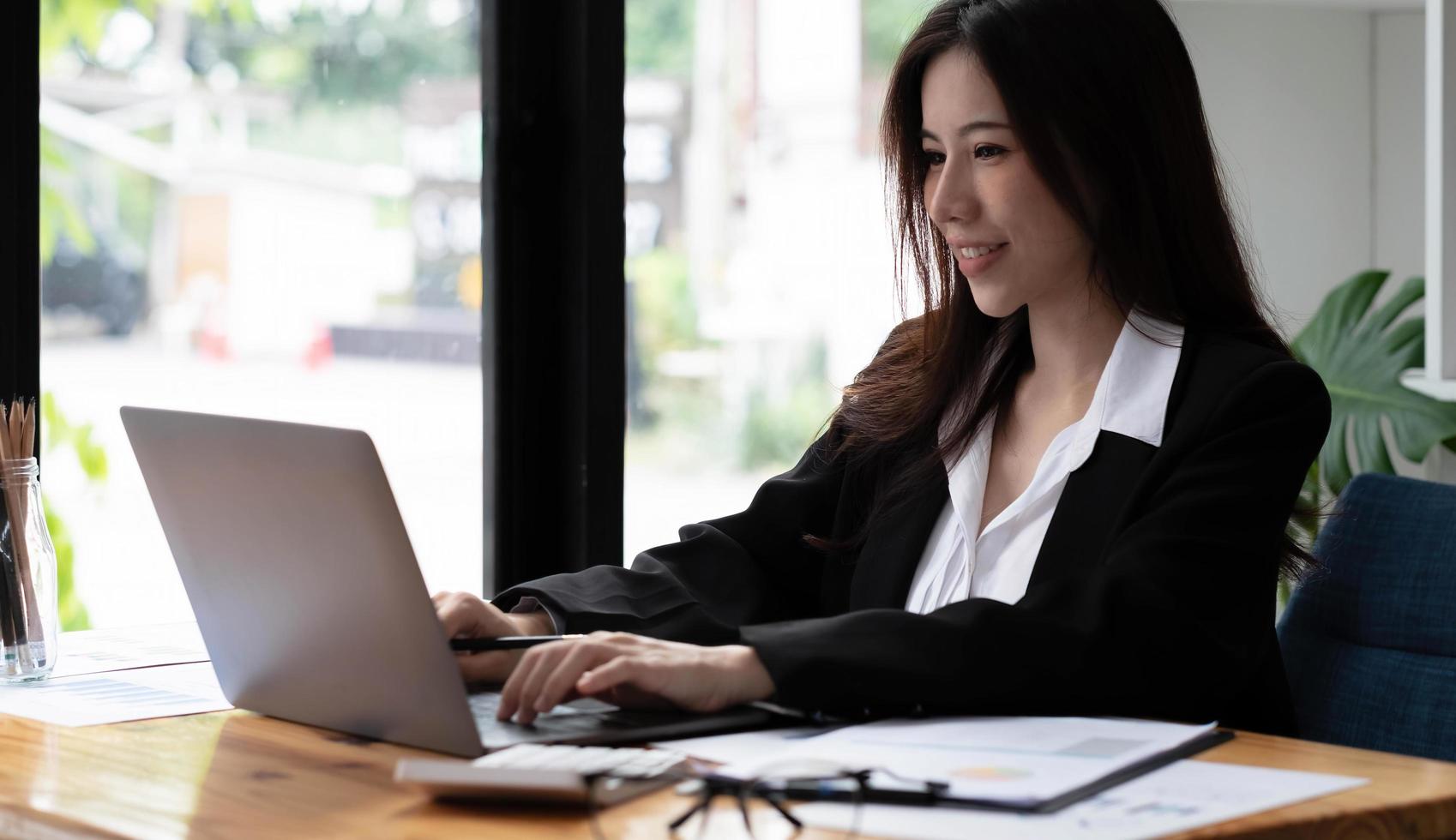 femme d'affaires asiatique utilisant un ordinateur portable pour faire des finances mathématiques sur un bureau en bois au bureau, fiscalité, comptabilité, concept financier photo