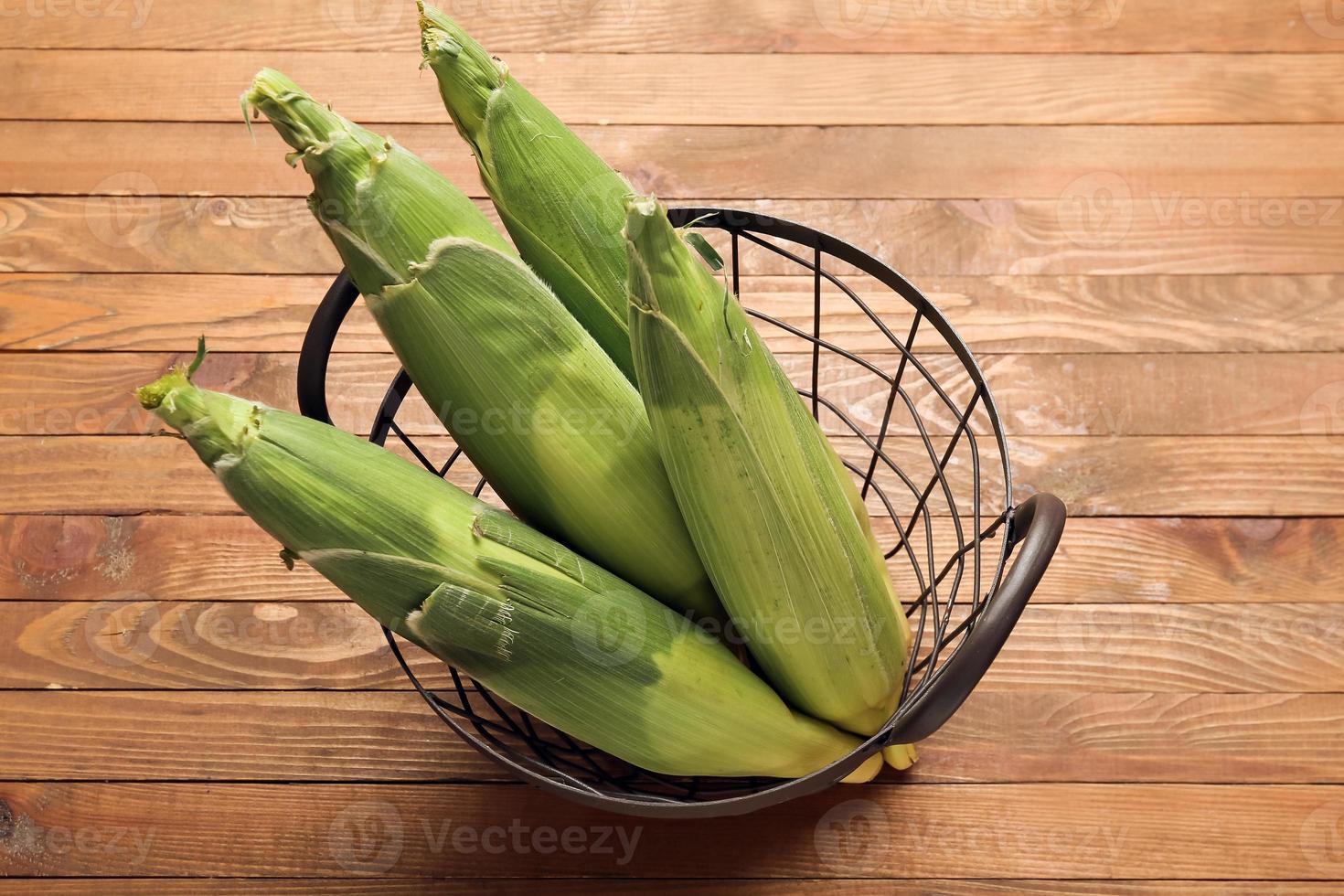 panier avec des épis de maïs frais sur fond de bois photo