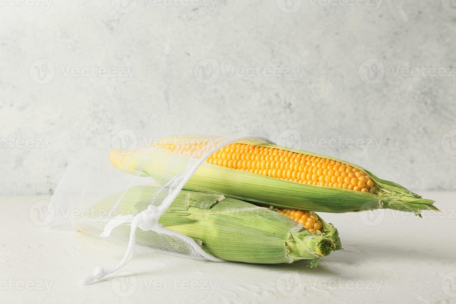 sac d'épicerie avec des épis de maïs frais sur fond clair photo