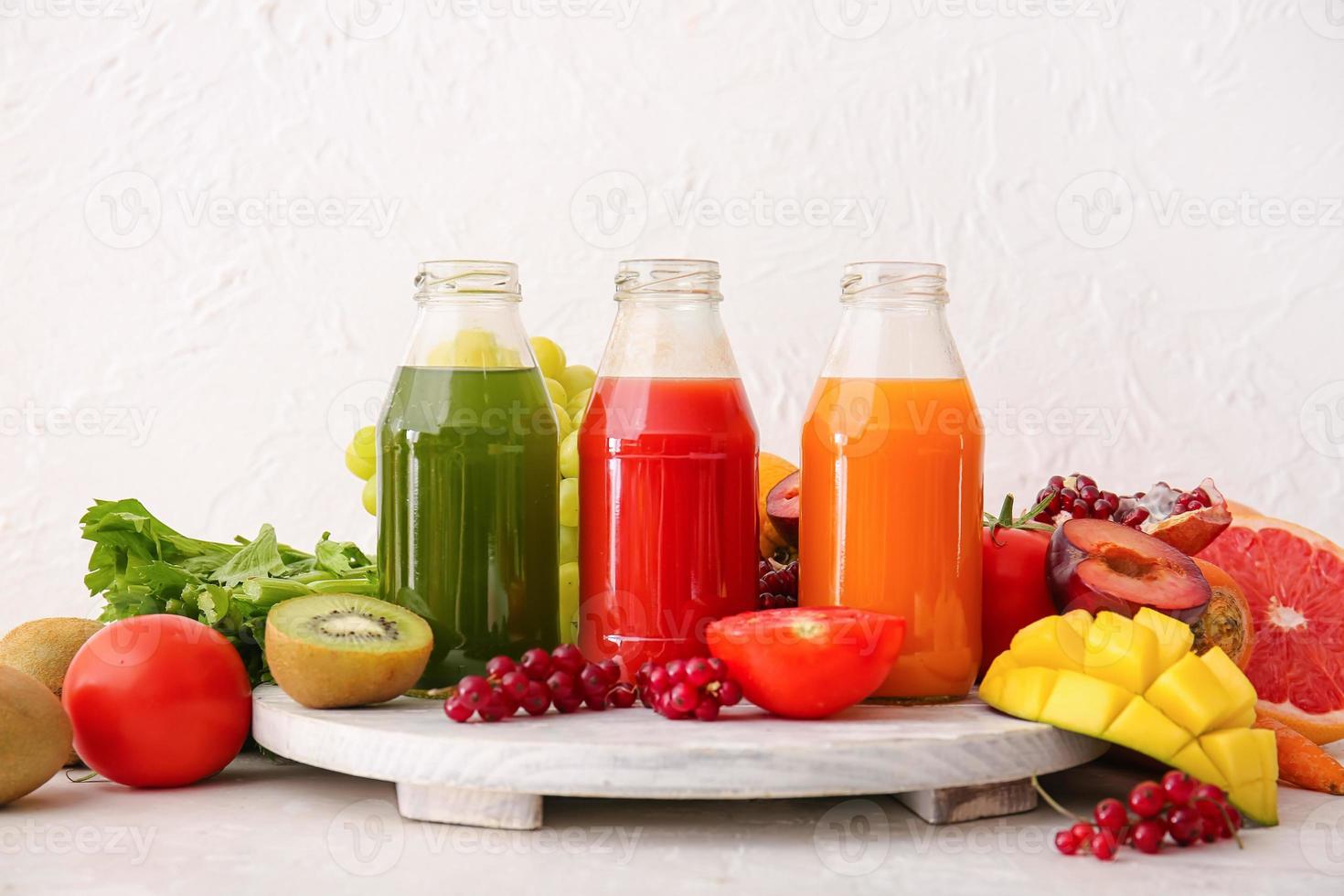 bouteilles de jus sains, fruits et légumes sur fond clair photo