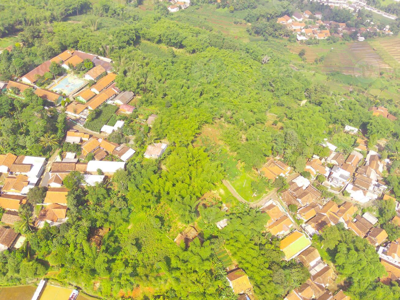 oiseau œil vue de village parmi riz des champs dans bandung ville, Indonésie. paysage de les terres agricoles avec riz terrasse agricole cultures dans campagne. agricole champ. au-dessus de. coup de une drone en volant photo