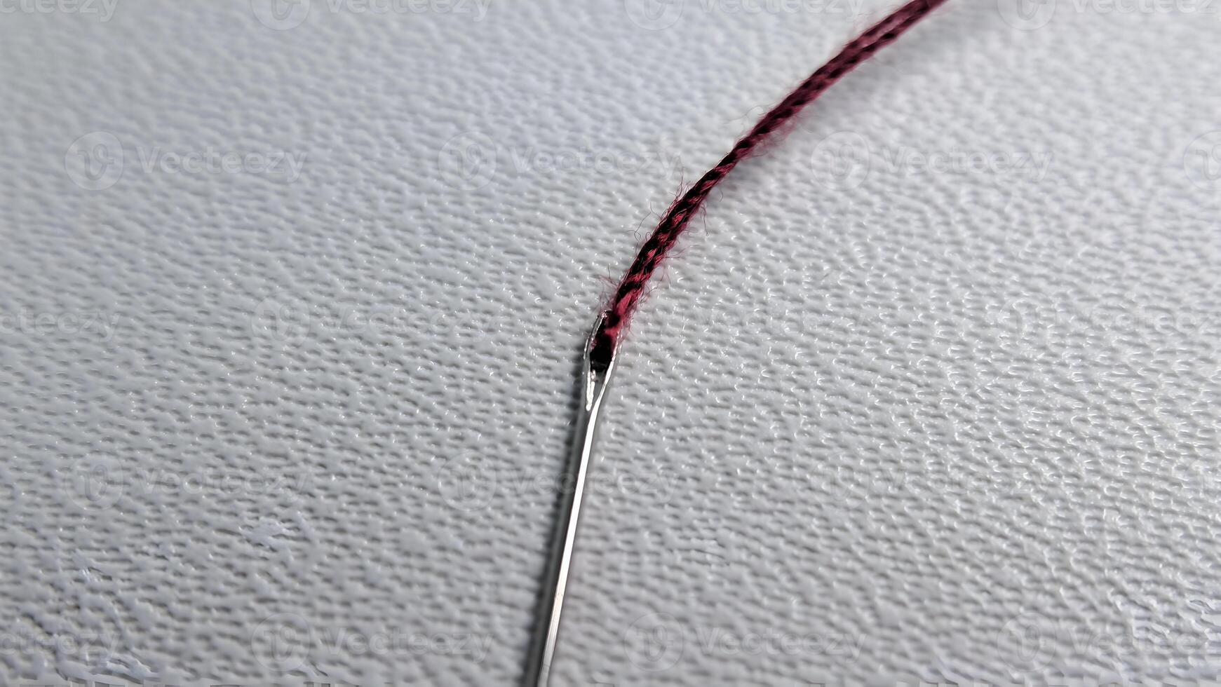 une aiguille avec rouge fil sur une blanc surface photo
