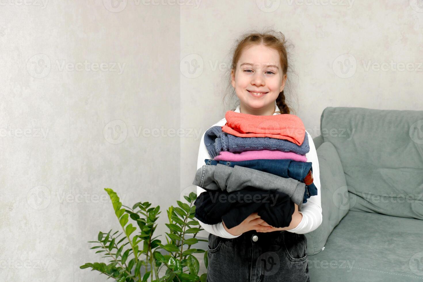 souriant fille en portant empiler de vêtements, charité et don photo