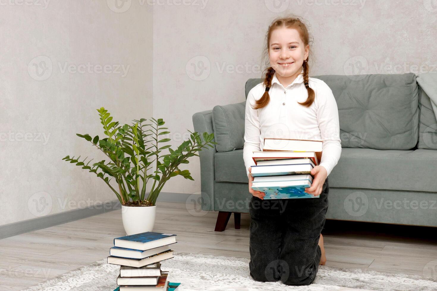 peu en riant fille avec une empiler de livres dans sa mains photo