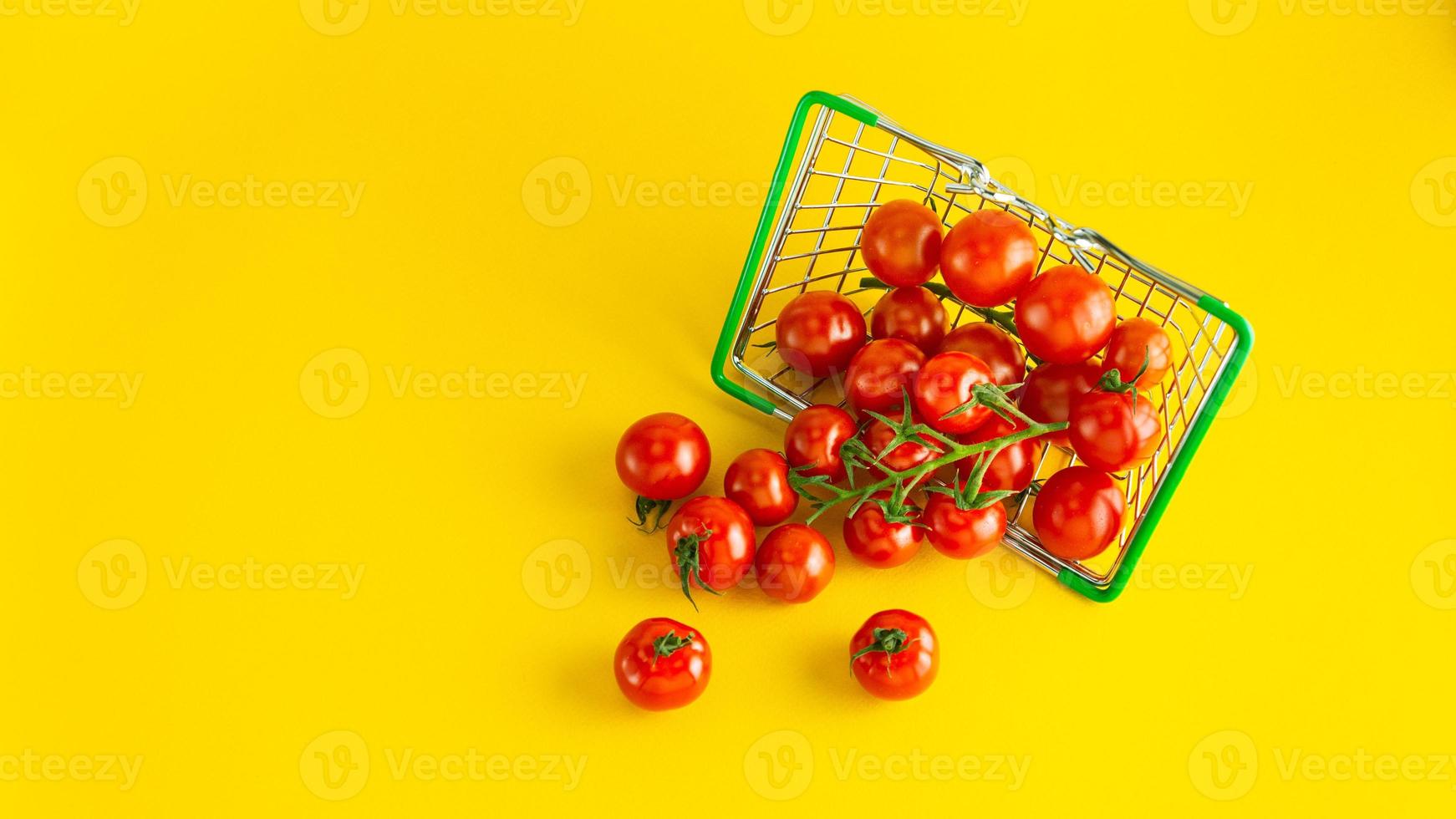 tomates cerises éparses dans un panier sur fond jaune vif avec une place vide pour une inscription. photo