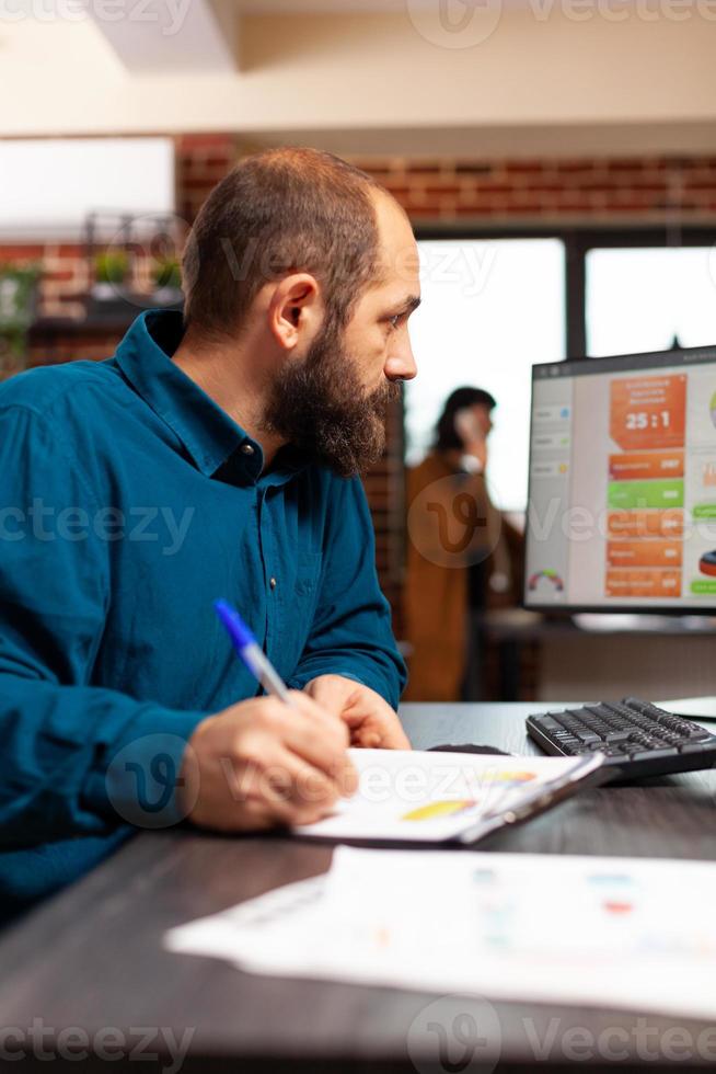 homme d'affaires assis au bureau écrivant une stratégie de gestion analysant des graphiques de données photo