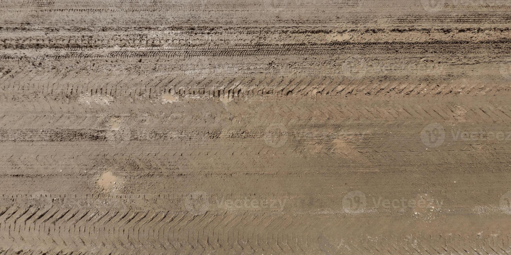 panorama de route de au dessus sur surface de gravier route avec flaques d'eau et voiture pneu des pistes photo