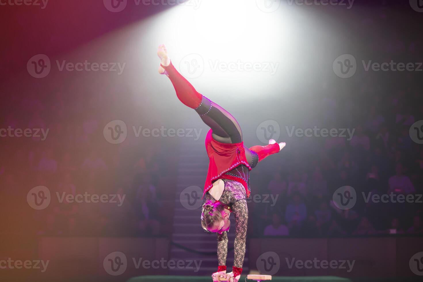 une gymnaste effectue dans une montrer. une fille gymnaste effectue une cirque acrobatique performance. photo