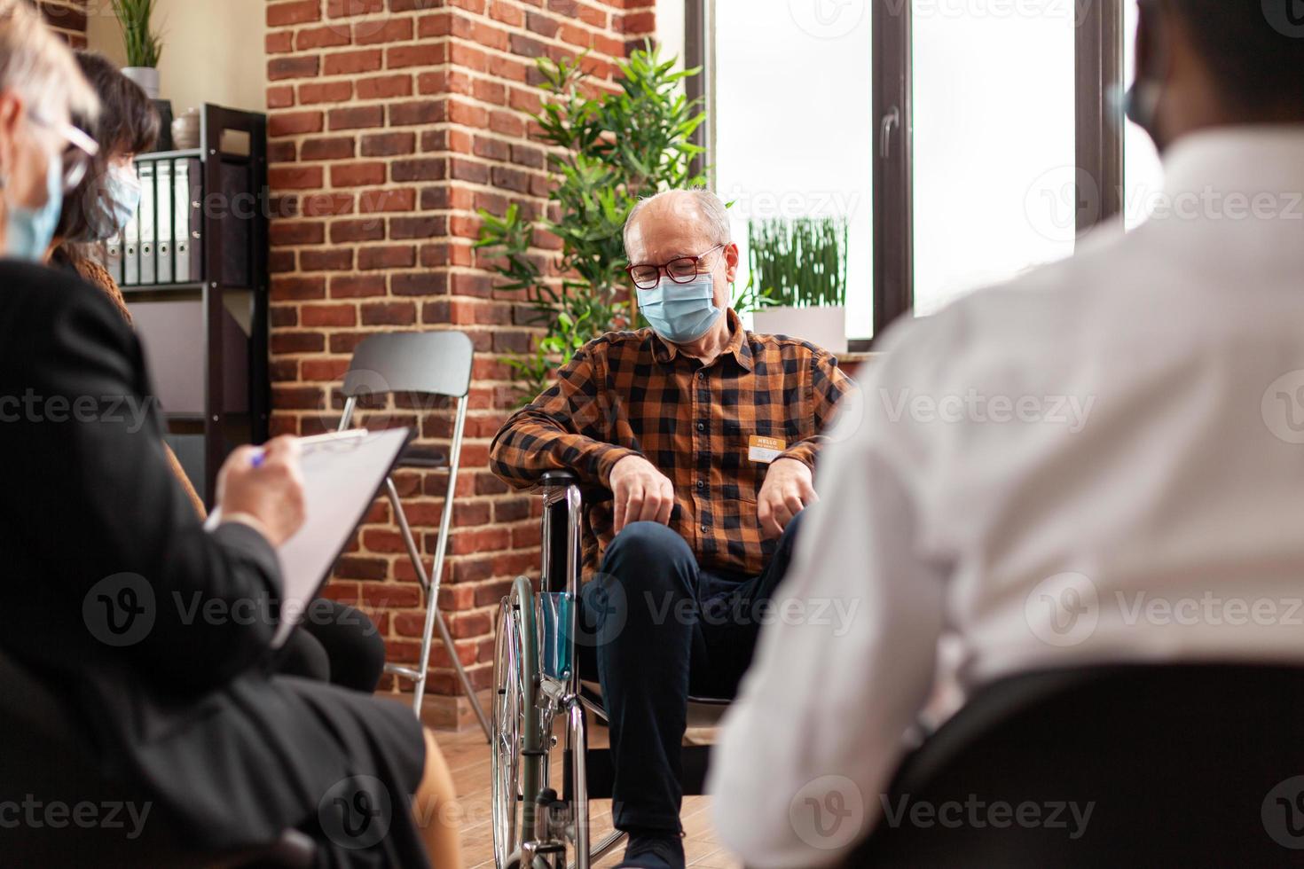 personne âgée avec masque facial assise en fauteuil roulant lors d'un programme de réunion photo