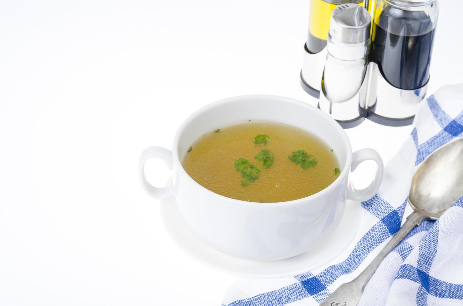 bouillon de viande transparent aux herbes dans une assiette blanche photo