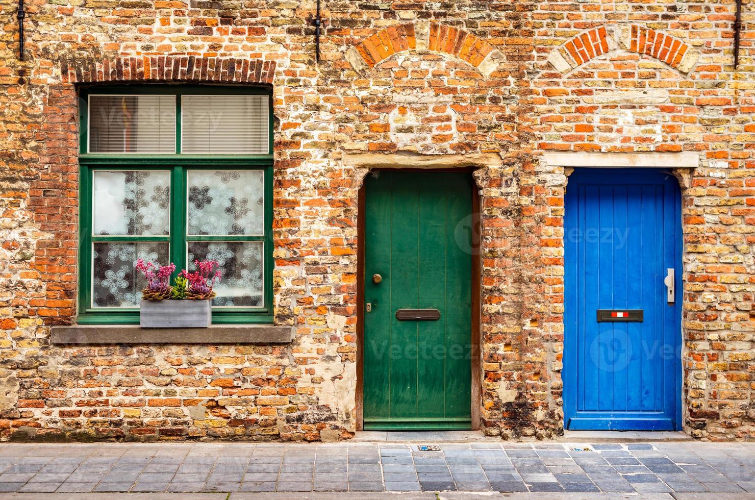 la façade d'une vieille maison en brique avec une fenêtre et deux portes en bois photo