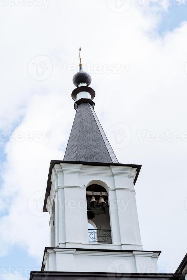 le cloche la tour, le blanc la tour de le église église avec cloches, le bronze cloche, le cloche sonnerie, à distribuer le du son à le entier district. photo