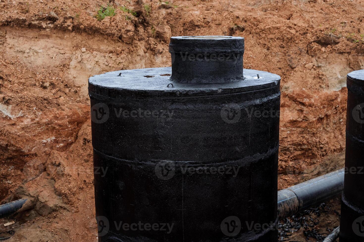 assainissement est creusé dans le sol, imperméabilisation avec noir résine, couvrant le bien avec une protecteur composé, l'eau la fourniture installation de béton blocs, rond Bien. photo