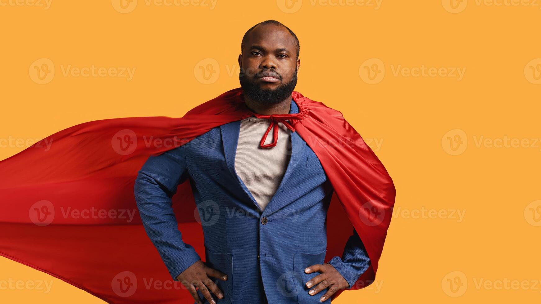 africain américain super-héros en volant avec rouge cap, isolé plus de studio arrière-plan, fléchissement muscles. homme portant manteau posant comme héros dans costume montrant courage et force, caméra b photo