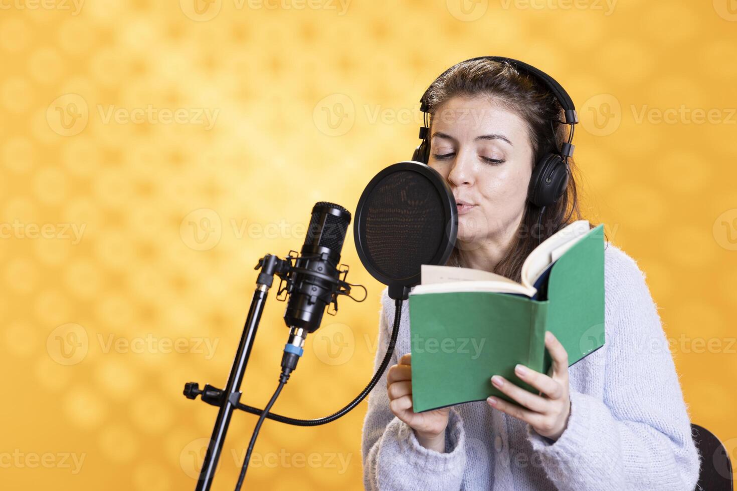 femme Faire voix off mot pour mot en train de lire de livre à produire livre audio. narrateur en utilisant narration compétences à divertir public tandis que produisant numérique enregistrement de roman, studio Contexte photo