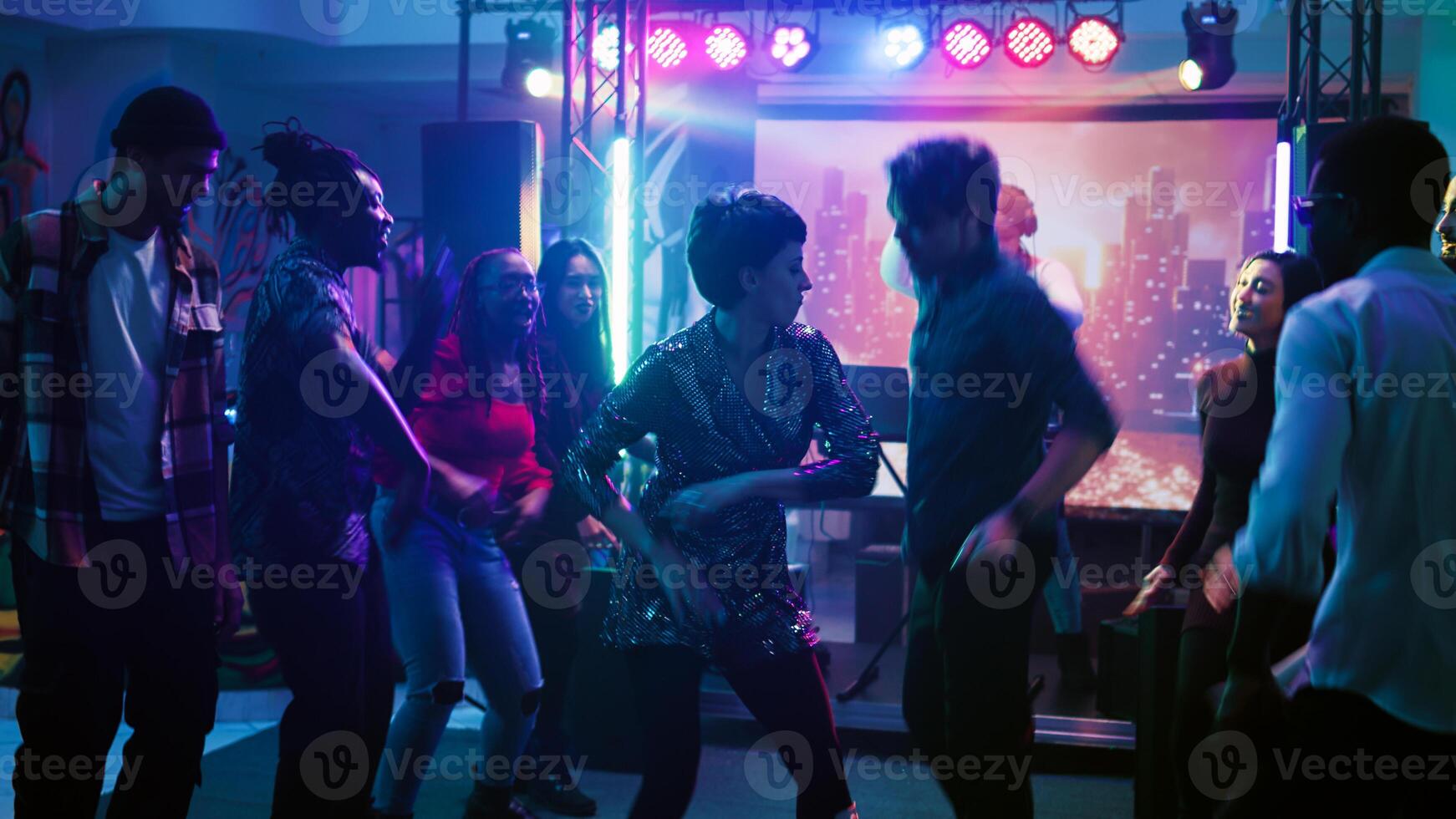 Hommes et femmes improviser Danse bataille à disco faire la fête, en mouvement autour Danse sol avec électronique la musique et étape lumières. Jeune danseurs ayant amusement montrant de froussard se déplace. ordinateur de poche tir. photo
