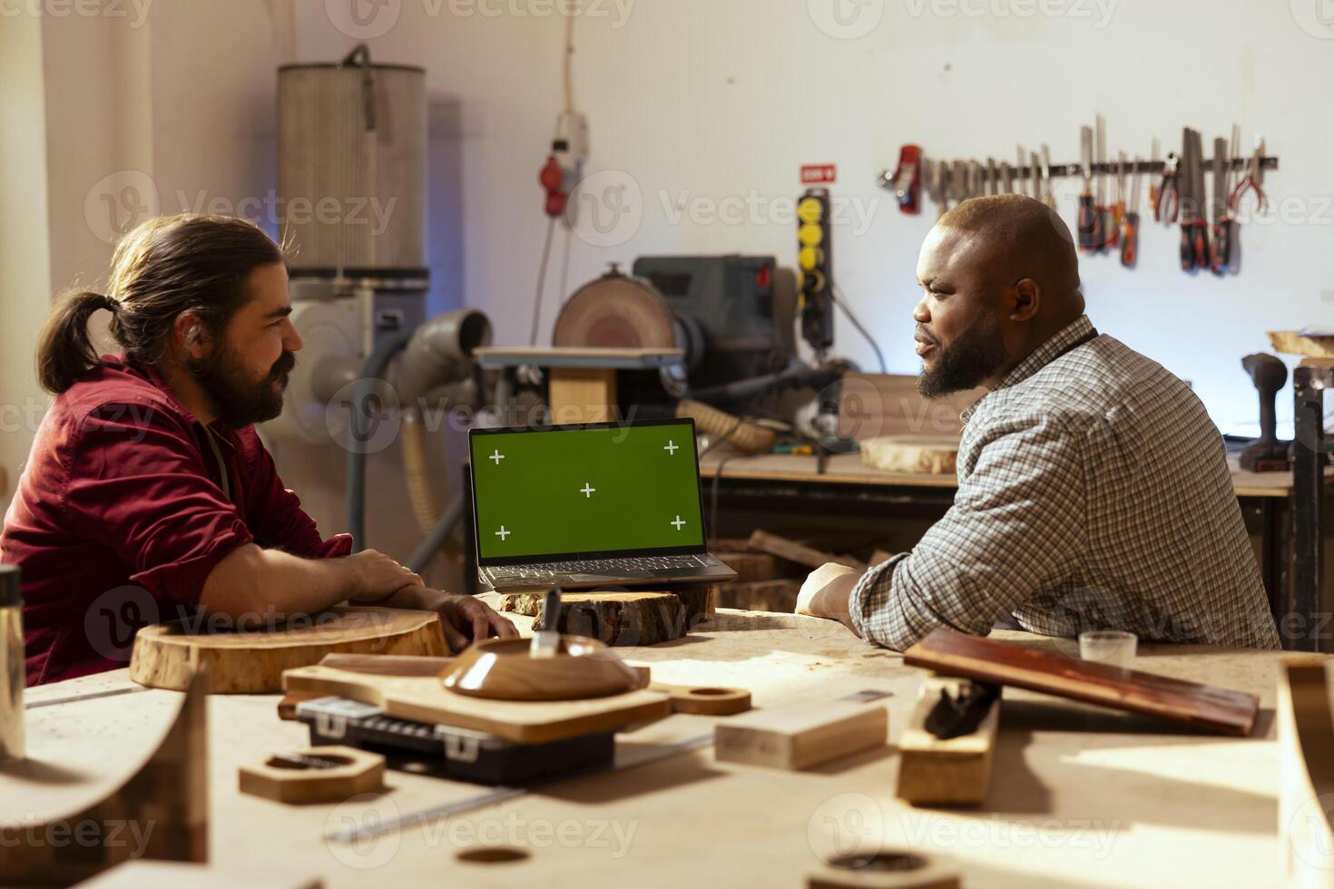 souriant artisan et collaborateur comparant bois art pièce avec schématique affiché sur isolé écran portable. travail du bois experts dans studio recoupement en bois objet avec chrominance clé carnet plan photo