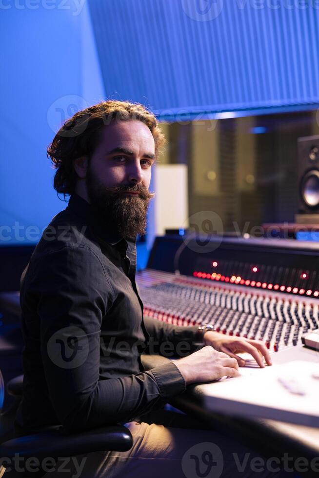 portrait de du son ingénieur travail avec l'audio console et numérique Logiciel sur PC dans professionnel enregistrement studio, produisant des pistes pour un album. technicien édition Nouveau Chansons dans contrôle chambre. photo