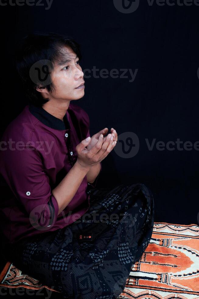 côté vue de une homme prier sur une prière tapis sur une noir Contexte. photo