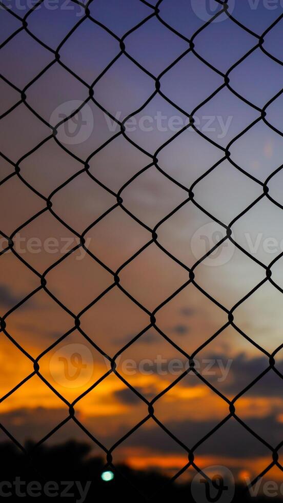 coup de le le fer net clôture contre le Contexte de un Orange ciel dans le après-midi. photo