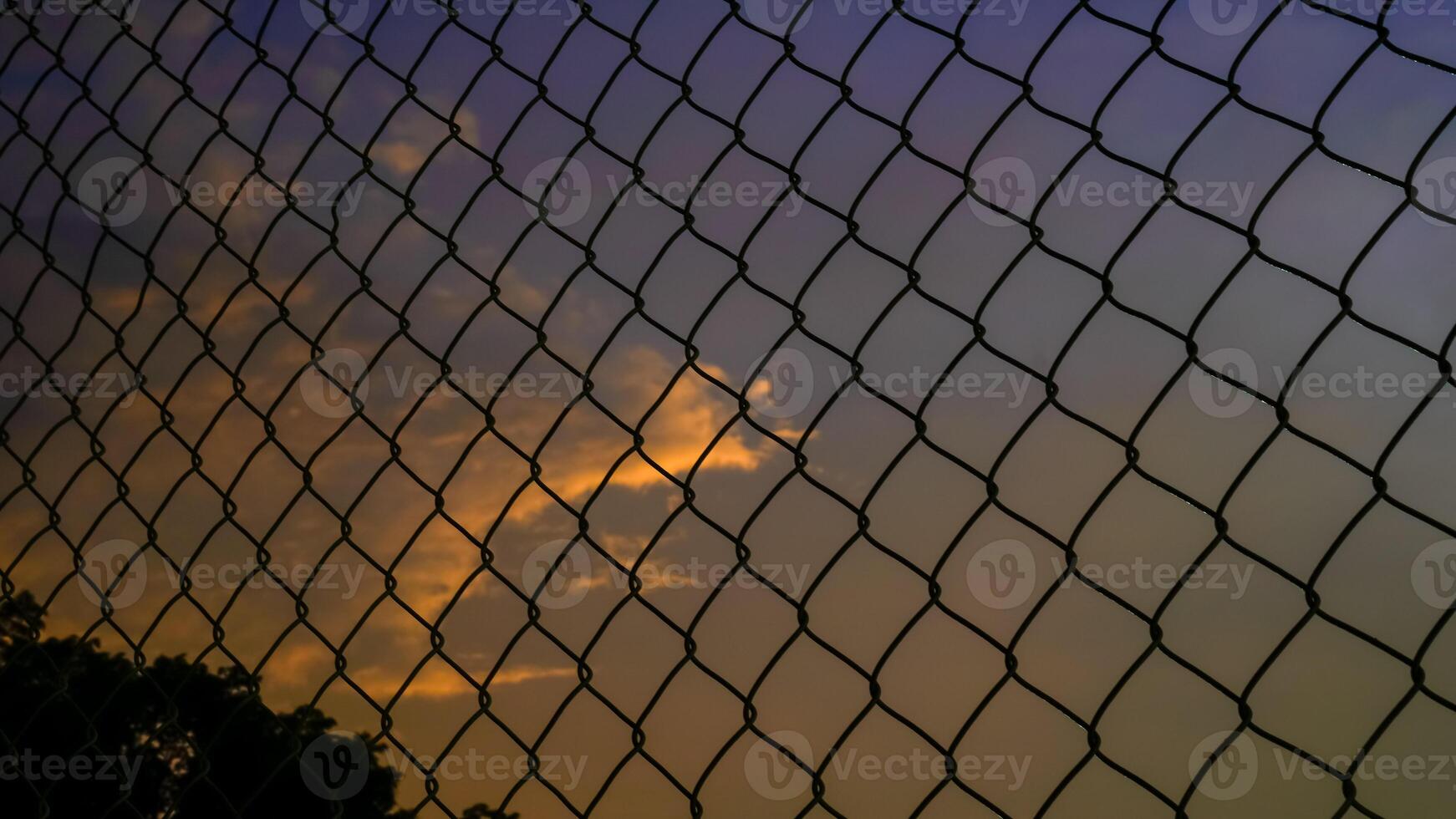 coup de le le fer net clôture contre le Contexte de un Orange ciel dans le après-midi. photo