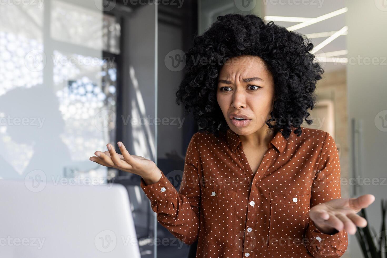 un africain américain femme d'affaires apparaît frustré tandis que parlant sur une appel. moderne Bureau toile de fond suggère une professionnel paramètre. photo