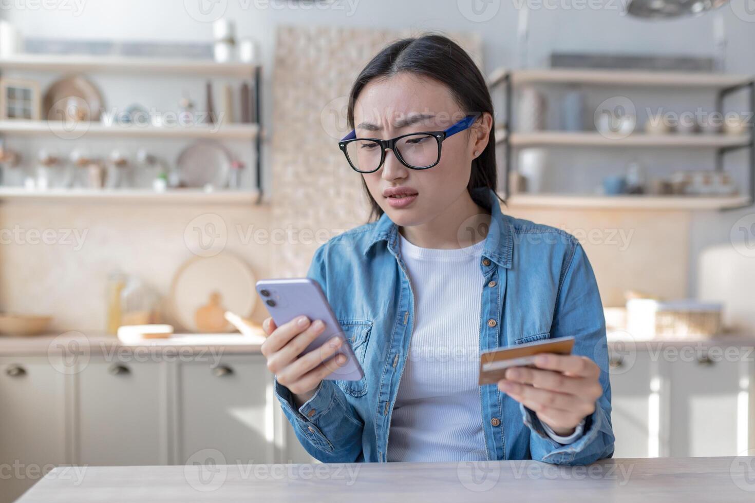 une Jeune asiatique femme essaie à faire une bancaire opération, les usages une téléphone et une banque crédit carte, déçu et malheureux avec le résultat photo